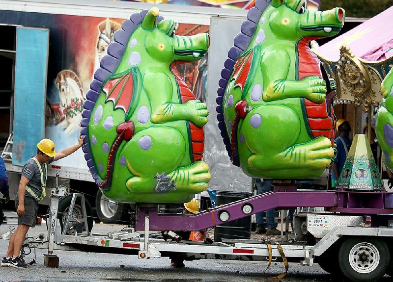 Fair Attractions worker Andries Oosthuizen gives one of the fair rides a pat on the back Monday morning as crews began tearing down and packing up at the State Fairgrounds in Little Rock. 