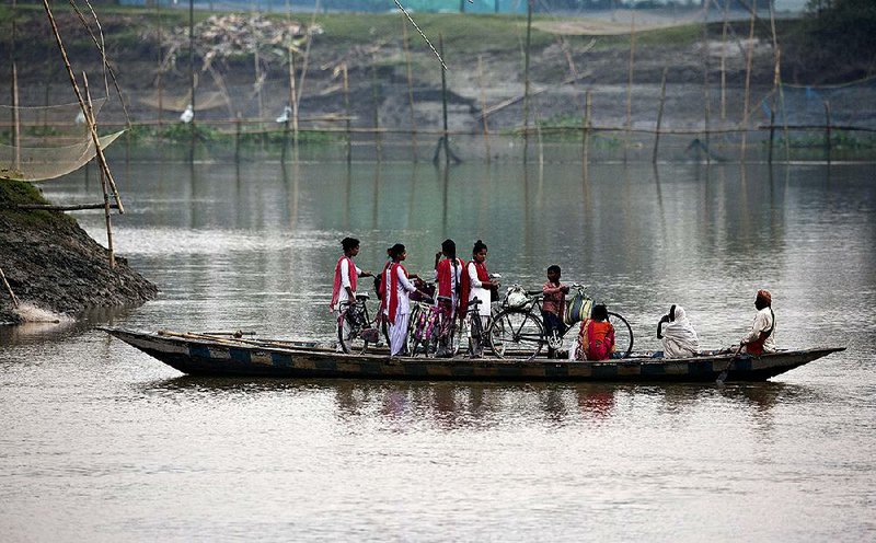 A boat carries schoolchildren and their bicycles Monday across the Brahmaputra river in India’s Kasoshila village. 