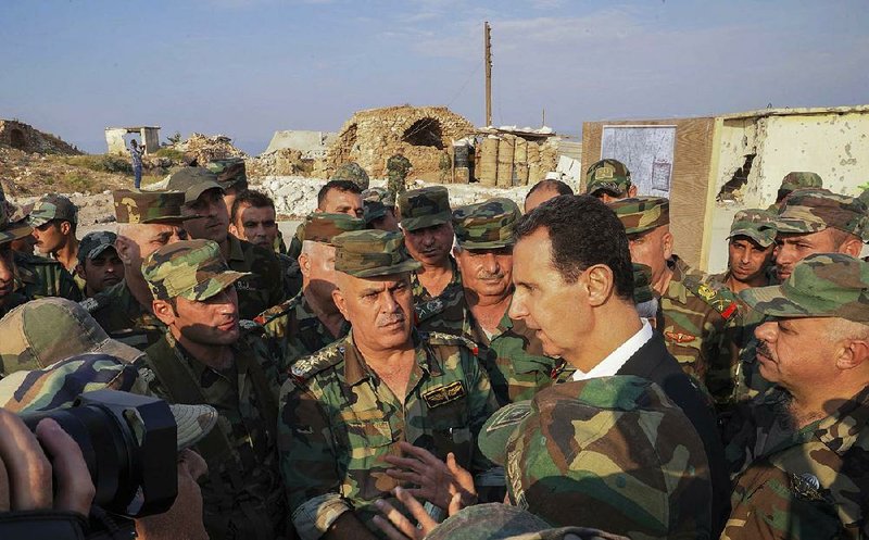 Syrian President Bashar Assad speaks with Syrian soldiers Tuesday in the strategic town of Habeet in northwestern Syria during a visit underlining his goal of regaining control of all territory along the border with Turkey. More photos at arkansasonline.com/1023turkey/