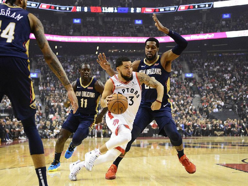 Toronto Raptors guard Fred VanVleet (23) drives past New Orleans Pelicans guard Jrue Holiday (11) and forward Derrick Favors (22) in the Raptors’ 130-122 overtime victory in the season opener for both teams. VanVleet scored a career-high 34 points for the defending NBA champions. 