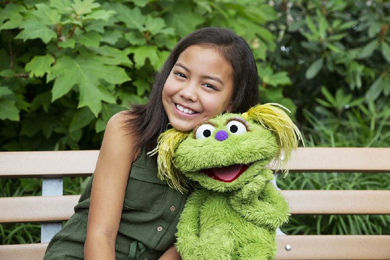 This undated image shows 10-year-old Salia Woodbury, whose parents are in recovery, with Sesame Street character Karli. Sesame Workshop is now addressing the problem of addiction.