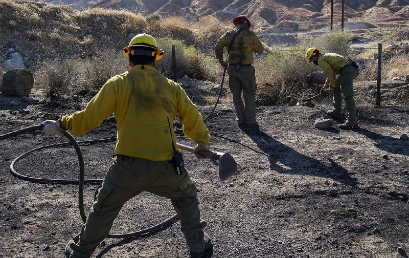 An engine crew looks for any remaining hot spots Thursday after battling a wildfire in Santa Clarita, Calif. More photos are available at arkansasonline.com/1026fires/