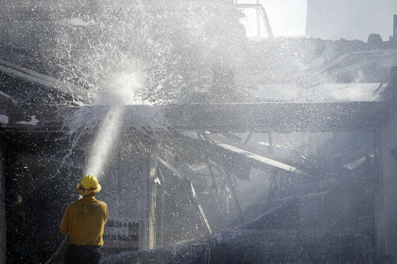 A firefighter tries to put out a residence fire caused by a wildfire Friday, Oct. 25, 2019, in Santa Clarita, Calif. 