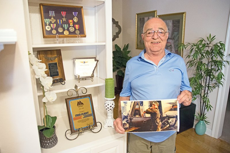 Retired Army Maj. James Edward Mason III of Searcy displays some of his military medals in a shadowbox, as well as plaques of appreciation for his service to the MedFlight program in Arkansas. He also shows a photograph of him and his bullet-riddled helicopter in Vietnam, noting that he was 22 when he served with the Army in Vietnam.