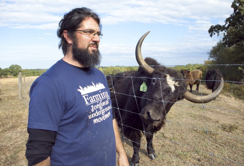 Yak farmer Robert Cissell stands next to the fence separating his yak herd from his domestic cattle at his farm in Buckingham County, Va. (Photo by Timothy C. Wright via The Washington Post)