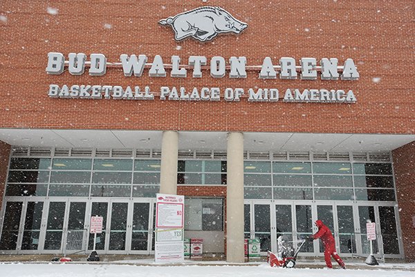 Workers clear snow from the west entrance of Bud Walton Arena on the university campus as snow falls Sunday, Feb. 2, 2014, in Fayetteville.
