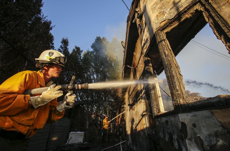 Firefighters work on a house destroyed by a wildfire called the Getty Fire in Los Angeles, Monday, Oct. 28, 2019. (AP Photo/Ringo H.W. Chiu)