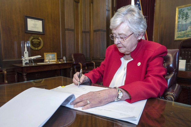 FILE-In this Wednesday, May 15, 2019 file photo released by the state shows Alabama Gov. Kay Ivey signing a bill that virtually outlaws abortion in the state, in Montgomery, Ala. U.S. District Judge Myron Thompson on Tuesday, Oct. 29, 2019, has blocked an Alabama abortion ban that would have made the procedure a felony at any stage of pregnancy in almost all cases. (Hal Yeager/Alabama Governor's Office via AP, File)