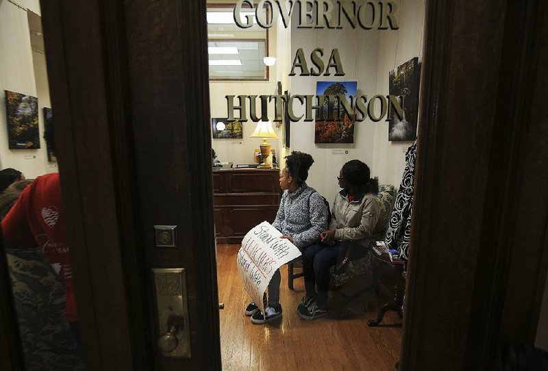 Parkview High School students Morgan Peters (left) and Diane Cooper, both 18, sit in the lobby of the governor’s office Wednesday at the state Capitol as they wait to see if Gov. Asa Hutchinson will meet with them. More photos are available at arkansasonline.com/1031lrsd/. 