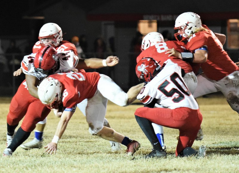 RICK PECK/SPECIAL TO MCDONALD COUNTY PRESS McDonald County's Levi Helm (50) goes low while teammate Junior Eliam goes high to bring down Seneca's Trey Wilson during the Mustangs' 34-27 loss on Oct. 25 at Seneca High School.