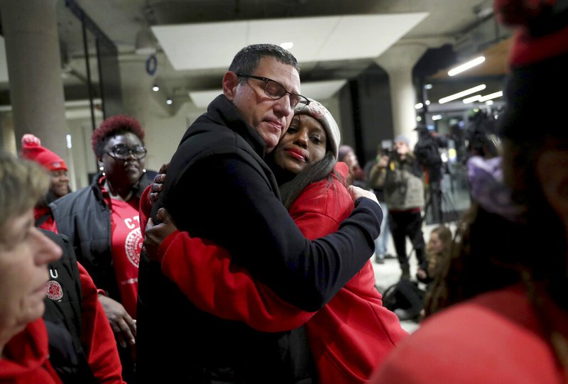 In this Wednesday, Oct. 30, 2019, Chicago Teachers Union President Jesse Sharkey and vice-president Stacy Davis Gates share a hug after speaking to the media following a CTU House of Delegates meeting at the Chicago Teachers Union Center in Chicago. (Chris Sweda/Chicago Tribune via AP)