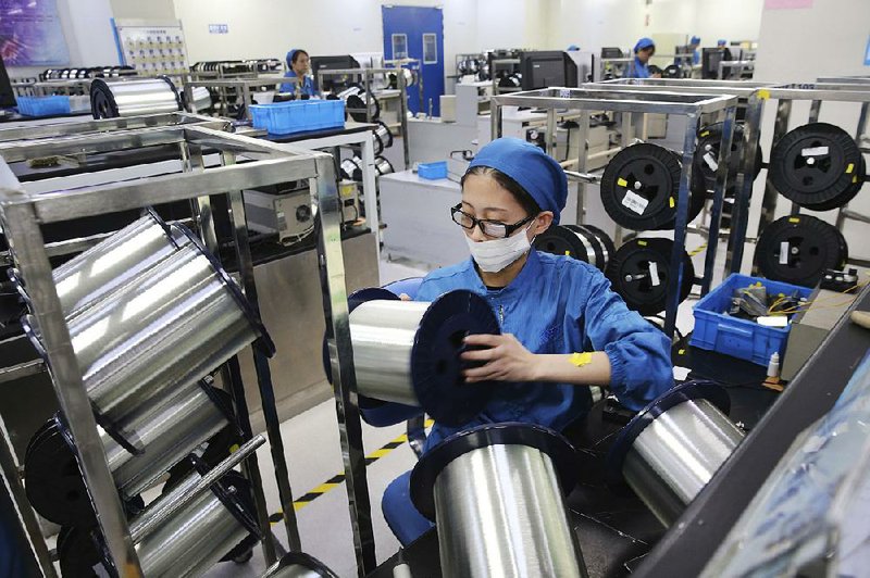 A woman works earlier this year on a production line in a fiber-optics factory in Nantong, China. An industry group reported Thursday that China’s factory activity shrank more sharply than expected in October amid weak consumer demand and a tariff war with Washington. 