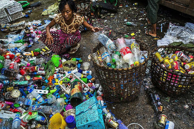 A woman collects plastic bottles from a pile of trash in Yangon, Burma, in September. The declining presence of shared terra-cotta water pots — replaced in some cases by plastic bottles with tin cups chained to them — is just one small change amid great upheaval in Yangon.