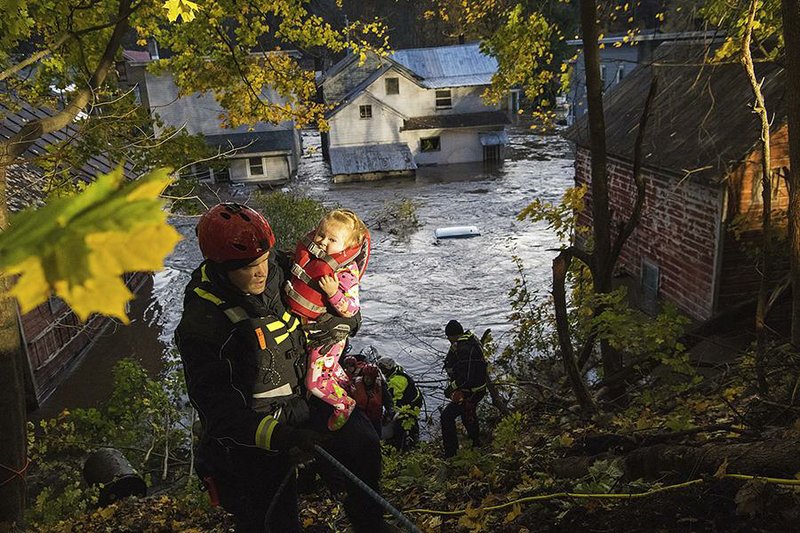 A rescuer carries a young girl to safety Friday after saving her from a flooded house in Dolgeville, N.Y. Storms struck the Northeast on Halloween night, causing flooding and downing power lines. At least two people were killed. More than 450,000 customers in the region were still without electricity Friday afternoon. 