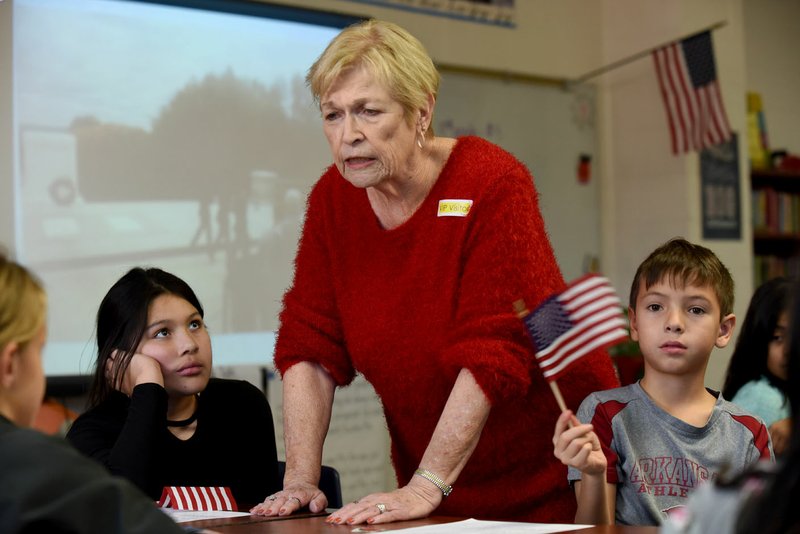 NWA Democrat-Gazette/DAVID GOTTSCHALK Bonnie Cherry, a retired teacher whose father served in World War I, speaks Friday with fourth-grade students in Kacee Scott's class at Hunt Elementary School in Springdale. Hunt spoke to the children about the history of the poppy flower, the significance of World War I and Veterans Day. Cherry, along with Dorothy Cardiel, a veteran and member of the VFW Auxillary, handed out stickers, U.S. flags and a poppy.