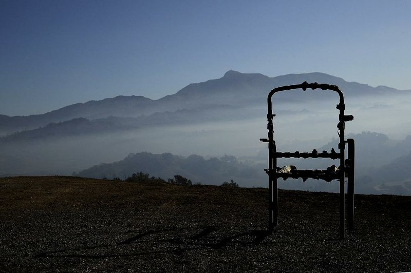 A charred lawn chair sits near a smoke-filled valley Friday near Healdsburg in Northern California’s Sonoma County.