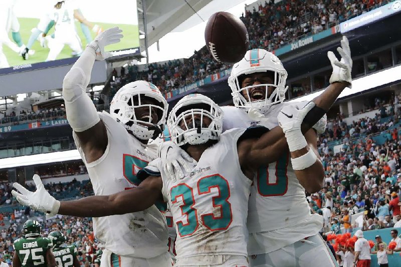 Miami Dolphins outside linebacker Jerome Baker (from left), cornerback Jomal Wiltz and defensive back Nik Needham celebrate after Wiltz made an interception during the first half Sunday against the New York Jets in Miami Gardens, Fla. The Dolphins won 24-18 for their first victory of the season.