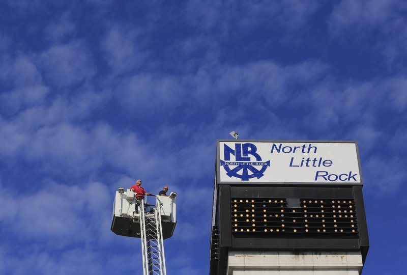 FILE — North Little Rock Fire Department Lt. Jason Bryant (right) maneuvers the bucket of ladder truck 7 into position as he and John McCullar of the North Little Rock City Services building maintenance staff work changing light bulbs on the buildings electronic time and temperature sign in this Sept. 16, 2016, file photo.

