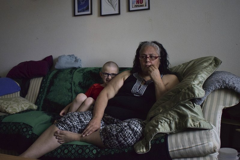 Leona Peterson and her son, Wayne, 6, sit in their home in Prince Rupert, British Columbia, Canada. When Peterson moved into the subsidized Indigenous housing complex with her family, a neighbor warned her about the poor quality of the drinking water. (Mackenzie Lad/Institute for Investigative Journalism/Concordia University via AP)