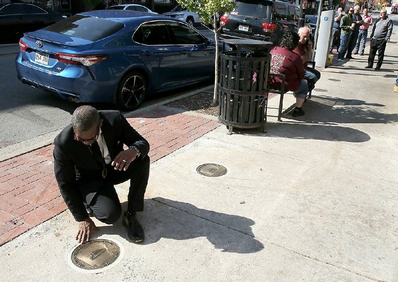 The Rev. Steven Bradley, a descendant of Ed Coleman, one of 12 black Phillips County sharecroppers wrongfully convicted of murder after a shooting that led to the bloody Elaine Massacre in 1919, kneels by Coleman’s marker Tuesday in Little Rock during an Arkansas Civil Rights Heritage Trail commemoration ceremony. Markers in honor of each of the sharecroppers were installed on the north sidewalk of President Clinton Avenue between Cumberland and Rock streets. More photos at arkansasonline.com/116massacre/ 