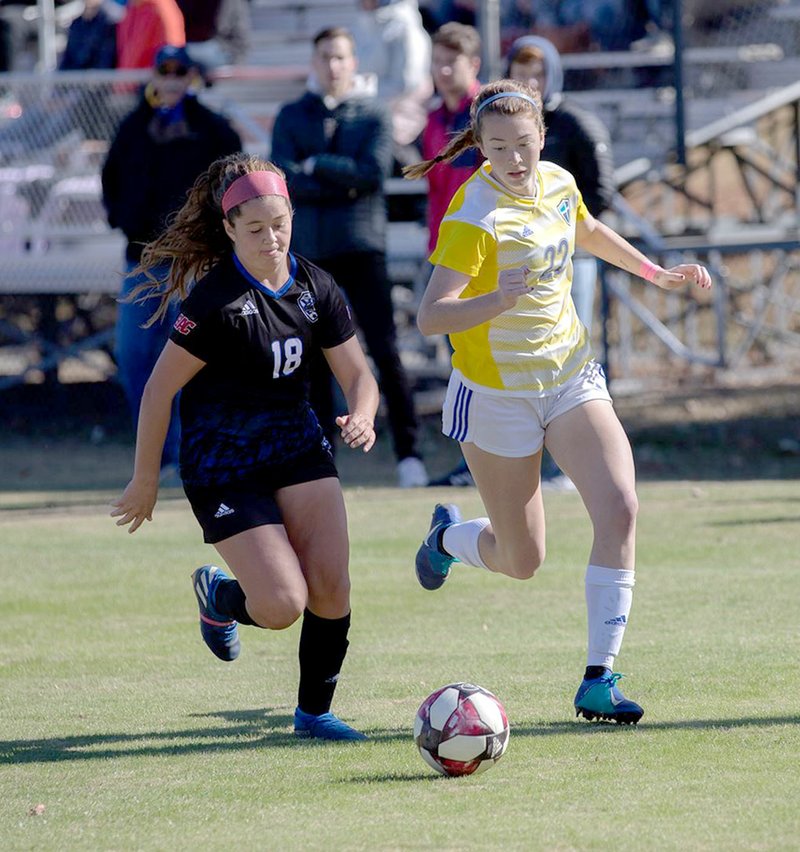 Photo courtesy of JBU Sports Information John Brown's Jenna Miller, right, runs with Southwestern Christian's Anne Marie Favarola during last Saturday's game at Alumni Field. JBU and SWC played to a 1-1 draw after two extra time periods.
