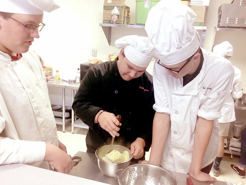 PHOTO SUBMITTED McDonald County High School student Dylan Gerow (center) mashes potatoes for the astro papa (mashed potato and steak quesadillas) as Keenan Meador (left) and Wade Rickman look on. The recipe is part of a contest to cook foods for NASA for space travel and the international space station.