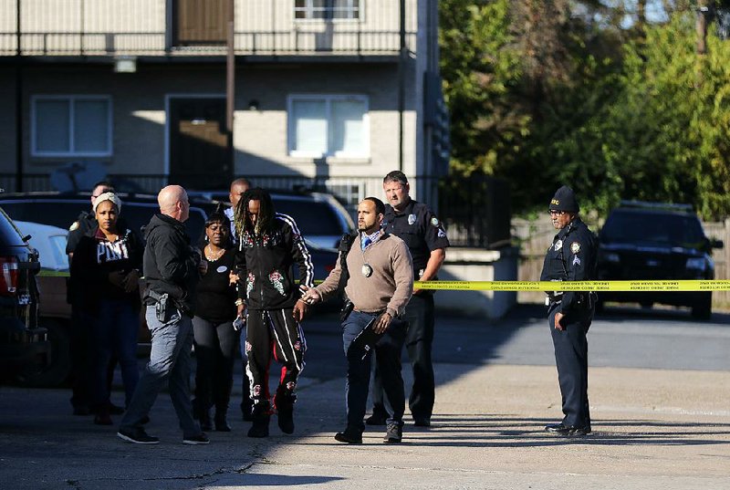 Little Rock police officers talk to witnesses after a man and a woman were found fatally shot at The Summit at Geyer Springs apartments on Friday. 