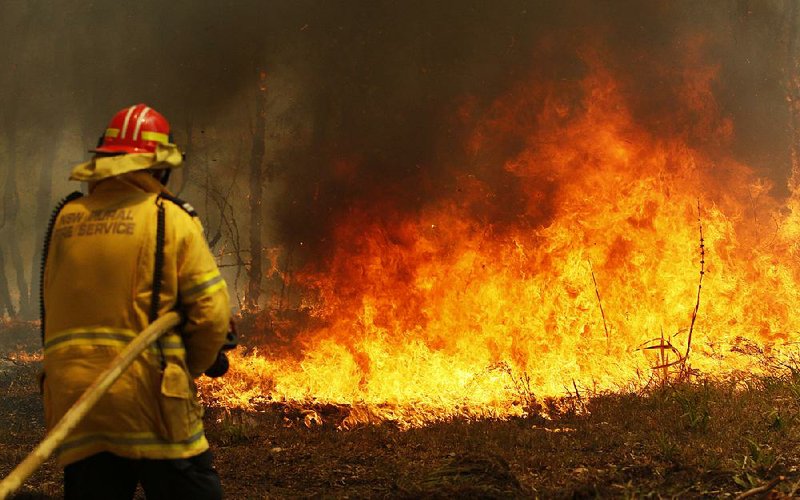 Firefighters work Saturday in Old Bar, Australia, to contain a bush fire, one of more than 70 blazes raging on the country’s eastern coast. Officials reported Saturday that the wildfires fanned by strong winds have killed three people and destroyed more than 150 homes. 