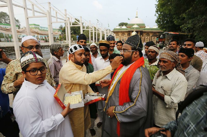 Indian Muslims in Ahmadabad, India, feed sweets to one another Saturday after the Supreme Court’s Hindu temple verdict. More photos are available at arkansasonline.com/1110temple/ 