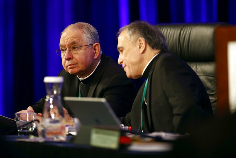 FILE - In this Monday, Nov. 12, 2018 file photo, Archbishop Jose Gomez of Los Angeles, vice president of the United States Conference of Catholic Bishops, left, sits with Cardinal Daniel DiNardo of the Archdiocese of Galveston-Houston, USCCB president, before the conference's annual fall meeting in Baltimore.