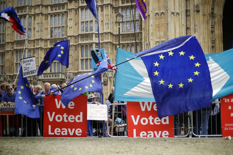 FILE - In this Sept. 3, 2019, file photo, leave and remain supporters try to block each others' banners as they protest opposite Parliament Square in London. 