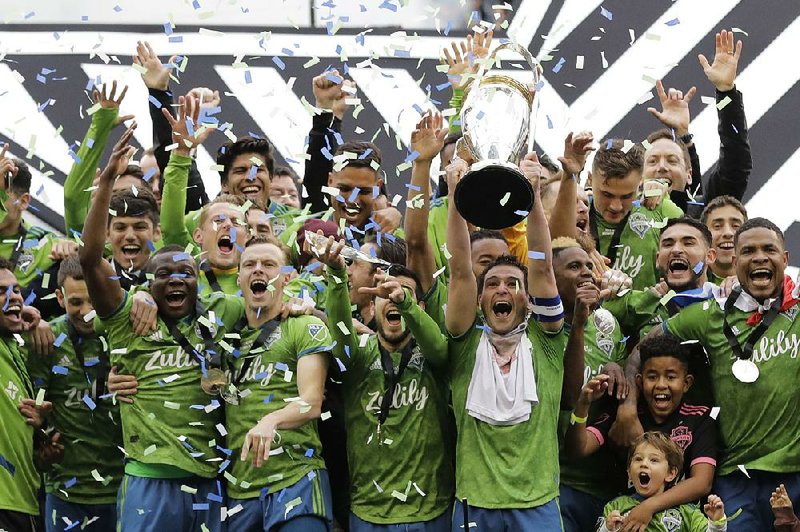 Seattle players celebrate as captain Nicolas Lodeiro lifts the trophy after the Sounders beat Toronto FC 3-1 Sunday to win the MLS Cup.