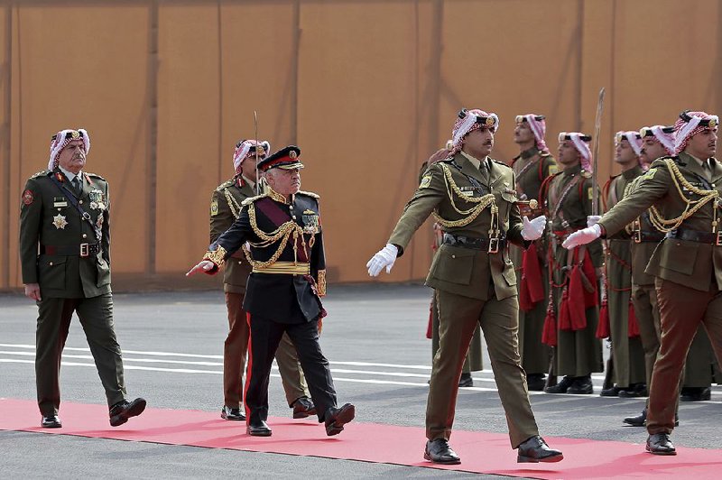 Jordan’s King Abdullah II (third from left) reviews an honor guard Sunday before his speech to Parliament in Amman. 