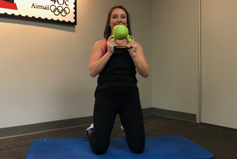 Arkansas Democrat-Gazette/CELIA STOREY Group exercise instructor Lauren Ritchie demonstrates the Kettlebell Arm Blast at Little Rock Racquet Club.