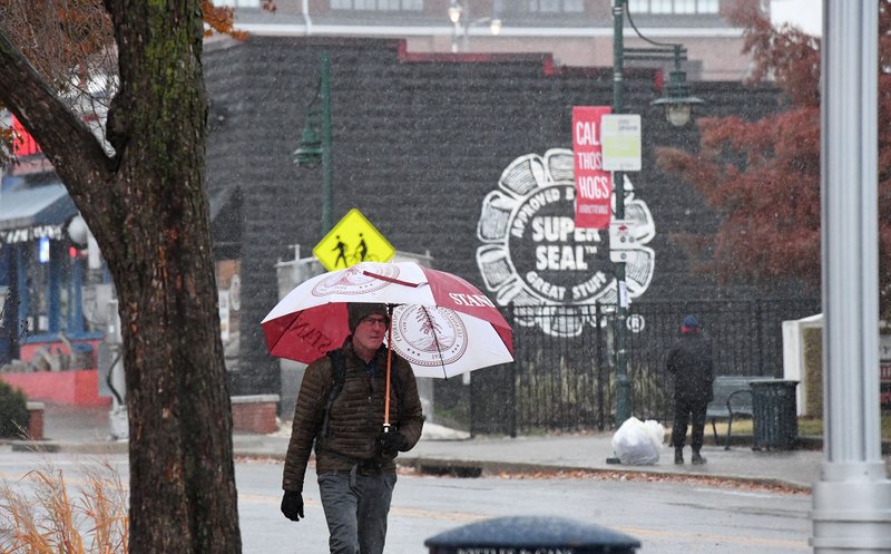 A pedestrian walks along Dickson St. in Fayetteville Monday Nov. 11, 2019 as sleet and snow fall. The National Weather Service is calling for clear skies the rest of the week with overnight lows in the teens and 20s. 