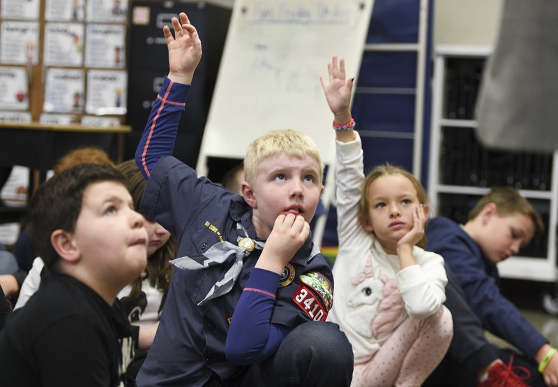 NWA Democrat-Gazette/CHARLIE KAIJO Dylan Maize (center) raises his hand to ask Jerry Moyer, U.S. Army sergeant of the 101st Airborne Division, a question about his military service, Monday at Cooper Elementary in Bella Vista. Moyer, a recipient of the Purple Heart, has visited Cooper Elementary every Veterans Day for the past nine years to talk about his military service.