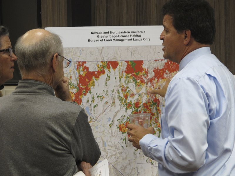 FILE - In this Nov. 7, 2017 file photo, Raul Morales, right, the U.S. Bureau of Land Management's deputy state director for Nevada, looks at a map of sage grouse habitat areas on BLM lands in Nevada and Northeastern California during a public meeting in Sparks, Nev. Federal land managers have withdrawn more than 500 square miles (1,295 sq. kilometers) of public land from a swath of eastern Nevada where oil and gas drilling leases were scheduled to be auctioned off on Tuesday, Nov. 12, 2019, after a judge blocked the Trump administration's attempt to ease protection of sage grouse habitat. (AP Photo/Scott Sonner, File)
