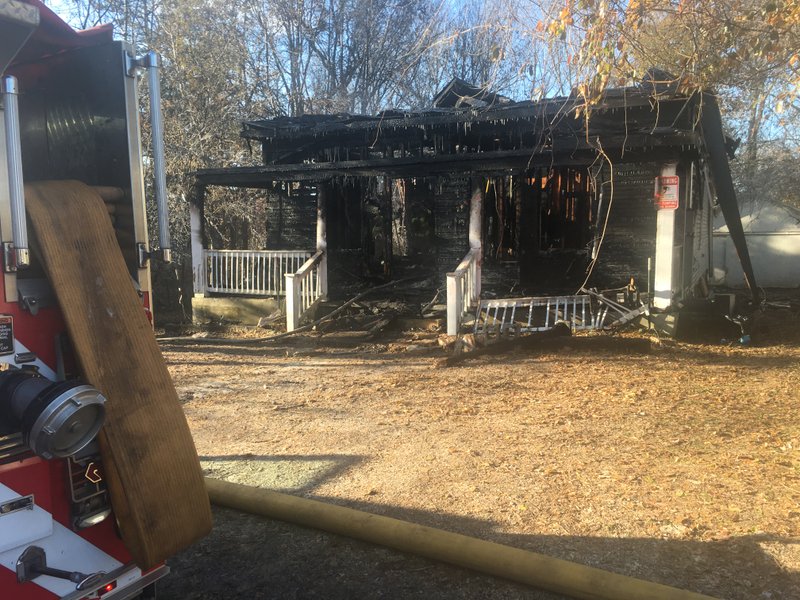 NWA Democrat-Gazette/FLIP PUTTHOFF A fire damaged the home at 520 Spring St. in Rogers early Tuesday morning. Police later arrested the home's occupant in connection with a stolen police car.