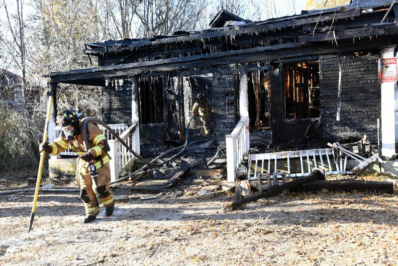 NWA Democrat-Gazette/FLIP PUTTHOFF Rogers firefighters work the scene Tuesday of a fire on Spring Street near downtown Rogers.