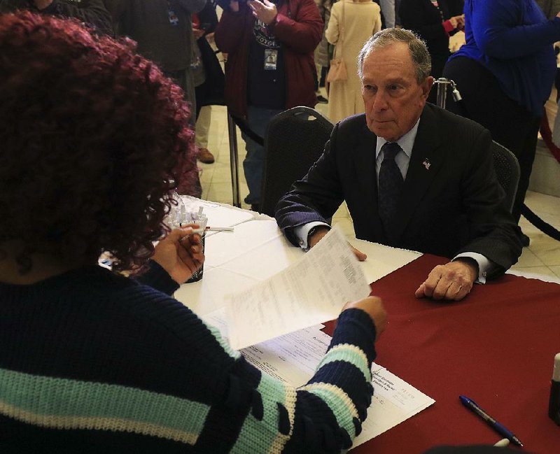 Raynetta Hansberry, election coordinator for the secretary of state’s office, checks Michael Bloomberg’s filing papers for the Democratic presidential primary at the state Capitol on Tuesday. After filing, the billionaire former New York mayor had lunch with Little Rock Mayor Frank Scott Jr. at Sims BBQ on Broadway.