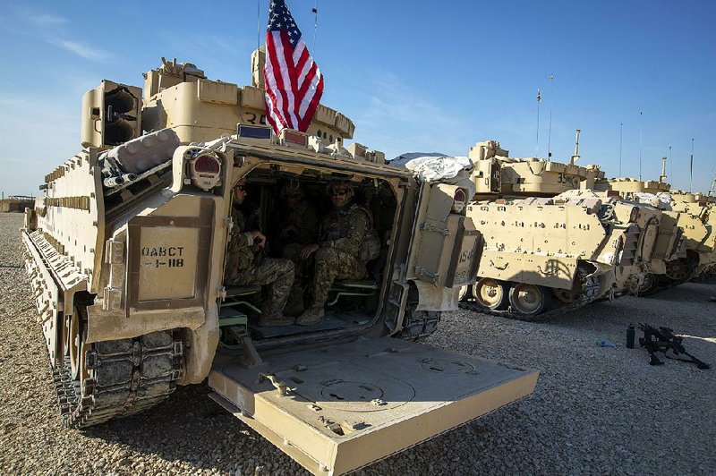 U.S. crewmen sit inside Bradley fighting vehicles Monday at an American military base at an undisclosed location in eastern Syria, part of a “force mix” that includes Apache helicopters.