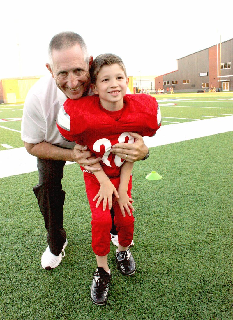 MARK HUMPHREY ENTERPRISE-LEADER Farmington head football coach Mike Adams celebrates with his grandson, Harlan Pettigrew, during Homecoming ceremonies at the school's new state-of-the-art $16 million Cardinal Stadium. Adams seeks out opportunities to teach his family and players life lessons through football. Friday's lopsided 49-20 loss at Harrison became such an occasion with the Cardinals ending their 2019 campaign with a 6-4 overall record and 3-4 league showing in the 5A West.