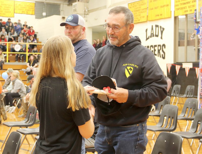 LYNN KUTTER ENTERPRISE-LEADER Willa Walters, a seventh grader with Prairie Grove Junior High School, greets Bud Moore, who served with the U.S. Army from 1969-1972, at the school's Veterans Day Assembly on Monday. Student Council members handed out a momento to all veterans who attended the program. Robert Beare, who served with the U.S. Navy and U.S. Army from 1997-2006, is in the background.
