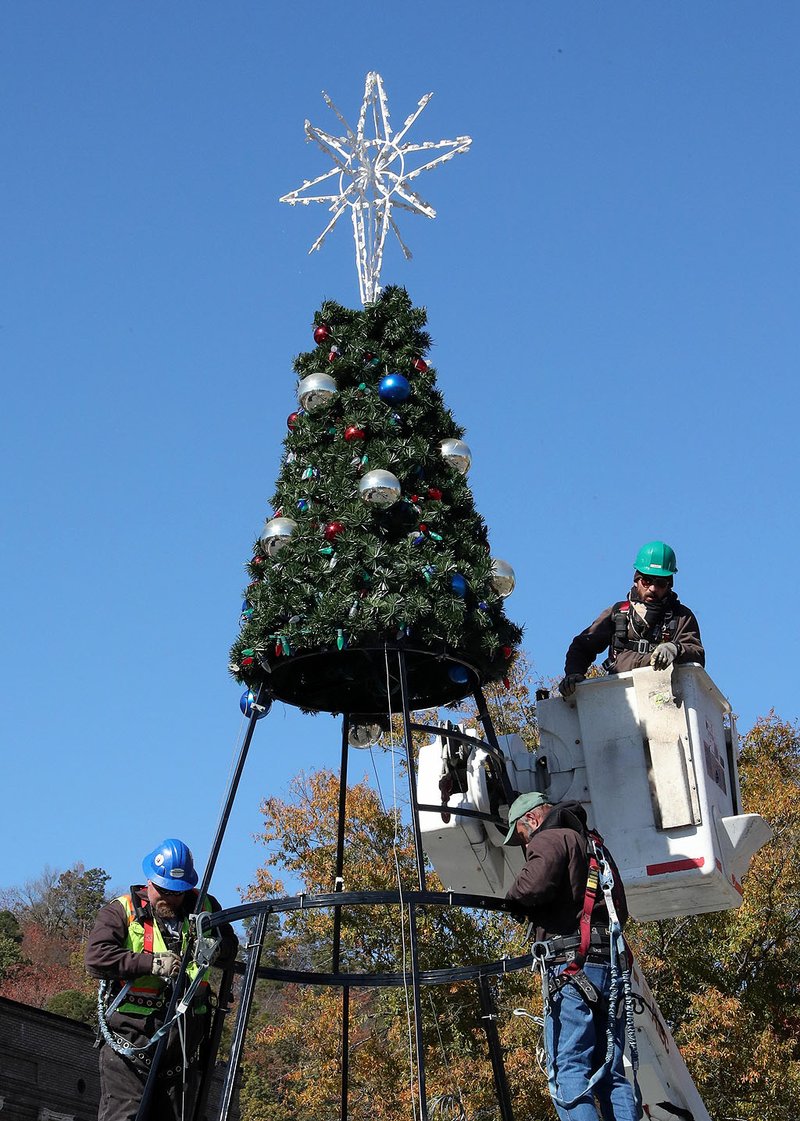 Hot Springs Parks &amp; Trails Department employees work near the top of a 30-foot-tall animated Christmas tree in Hill Wheatley Plaza on Tuesday. - Photo by Richard Rasmussen of The Sentinel-Record