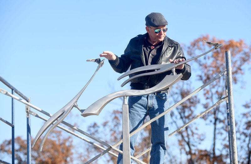 Amos Robinson, an artist from San Diego, installs Tuesday his metal sculpture Scissortails near the entrance to the Scissortail subdivision in Bentonville. Developers Bob David and Julie Vaught commissioned Robinson to create the sculpture depicting two scissor-tailed flycatchers in flight. The stainless steel birds move with the wind. A meet-the-artist drop-in event with Robinson will be held from 3 to 5 p.m. Thursday at the Scissortail clubhouse, 4407 Scissortail Drive in Bentonville. The public is welcome. NWA Democrat-Gazette/FLIP PUTTHOFF