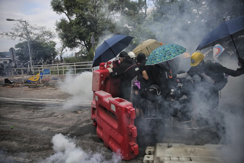 Students are surrounded by tear gas behind barricades during a clash with police at the Chinese University in Hong Kong, Tuesday, Nov. 12, 2019. Police fired tear gas at protesters who littered streets with bricks and disrupted morning commutes and lunch breaks Tuesday after an especially violent day in Hong Kong's five months of anti-government demonstrations. (Steve Leung/HK01 via AP)