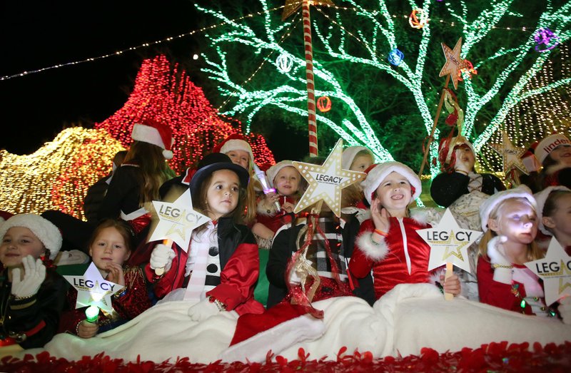 Performers with the Legacy Studio of Performing Arts of Johnson ride on a float in the kick-off parade for the 2018 Lights of the Ozarks event. NWA Democrat-Gazette/David Gottschalk