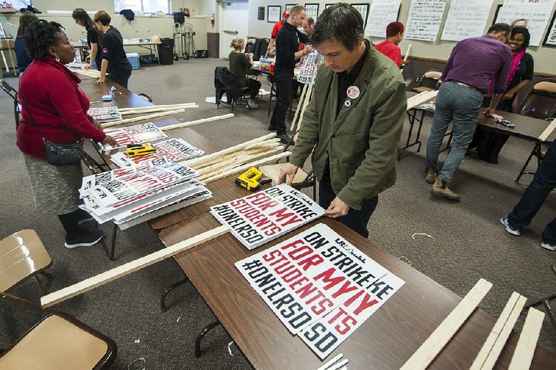 Josh McCallister, a teacher at Fulbright Elementary, helps make signs Wednesday at the Arkansas Education Association building near the state Capitol for today’s one-day strike by Little Rock teachers and support staff. 