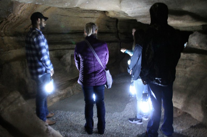 MEGAN DAVIS/MCDONALD COUNTY PRESS Tour-goers hold tight to their lanterns as tour guide and general manager Nicole Ridlen shares stories of mysterious occurrences in caves over the years. The lanterns served as the only source of light during the Boos and Brews Lantern Tours on Friday evening.