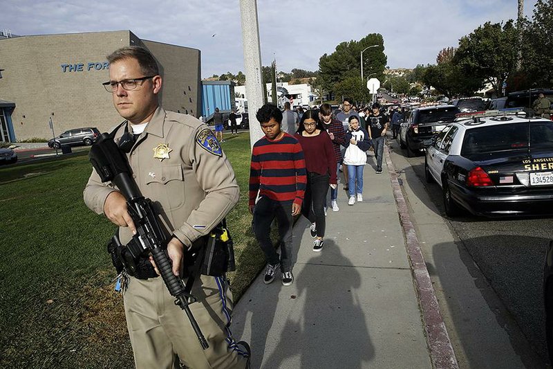 Los Angeles County sheriff’s deputies escort students out of a high school Thursday in Santa Clarita, Calif., where a student opened fire on his 16th birthday, killing a girl and a boy before turning his handgun on himself. He was hospitalized in grave condition. Three other youths also were hospitalized. More photos at arkansasonline.com/1115ca/ 